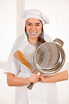 Young blonde chef woamn holds kitchenware as she prepares to coo