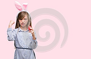 Young blonde child wearing easter bunny ears annoyed and frustrated shouting with anger, crazy and yelling with raised hand, anger