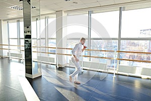 Young blonde dancer enjoys winning in white suit and makes warm