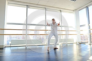 Young blonde dancer enjoys winning in white suit and makes warm