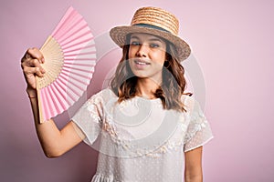 Young blonde fashion girl using wooden spanish hand fan on a hot summer day with a happy face standing and smiling with a
