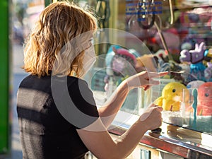 Young blonde female at the cashbox at an amusement park wearing a face mask