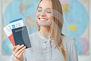 Young blonde female traveler in a tour agency holding passports close-up