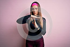Young blonde fitness woman wearing sport workout clothes over isolated background Doing time out gesture with hands, frustrated