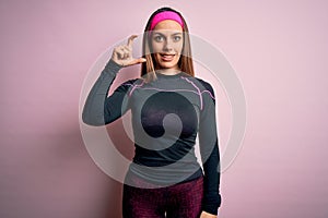 Young blonde fitness woman wearing sport workout clothes over isolated background smiling and confident gesturing with hand doing