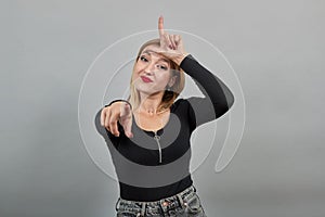 Young blonde girl in black jacket smiling woman taunts, shows that who has horns