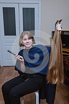 Young blonde girl cut very long hair at home