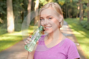 Young blonde girl drinking water during morning jogging