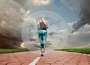 Young blonde girl evening jogging with great cloudscape