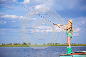 Young blonde girl fishing in lake
