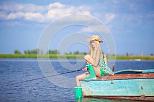 Young blonde girl fishing in lake