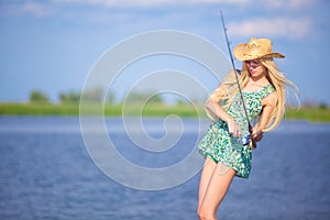 Young blonde girl fishing in lake