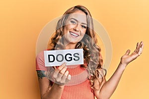 Young blonde girl holding paper with dogs message celebrating achievement with happy smile and winner expression with raised hand