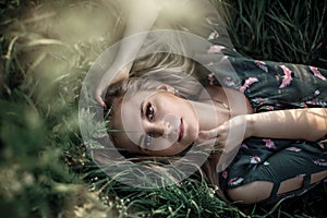 Young blonde girl with long hair lying in the grass.