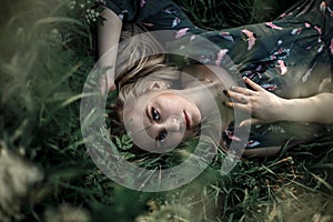 Young blonde girl with long hair lying in the grass.