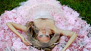 Young blonde girl in pink elegant dress falls back into the loop