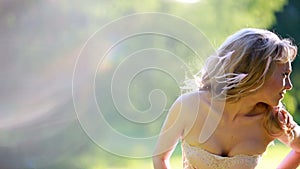 Young blonde girl in pink elegant dress standing in the woods