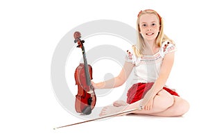 Young blonde girl poses with violin and bow on a white studio background