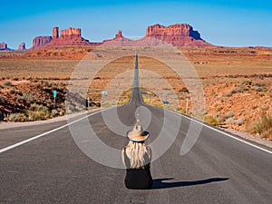 Young blonde girl sits in the center of Forrest Gump Point Road Monument Valley