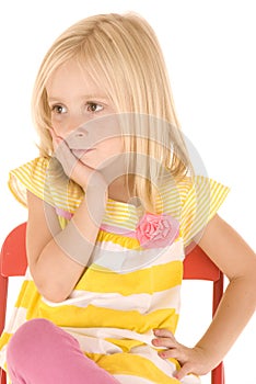 Young blonde girl sitting in chair thinking