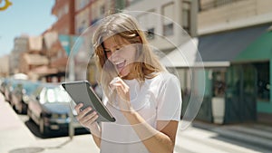 Young blonde girl smiling confident using touchpad at street