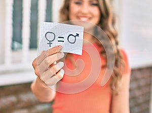 Young blonde girl smiling happy holding paper with gender equality concept walking at the city