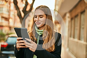 Young blonde girl smiling happy using touchpad at the city