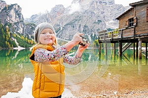 Young blonde girl smiling at Lake Bries and playing with camera