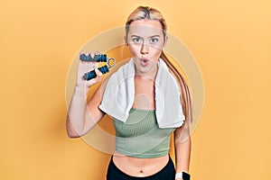 Young blonde girl training muscle with hand grip scared and amazed with open mouth for surprise, disbelief face