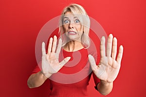 Young blonde girl wearing casual clothes afraid and terrified with fear expression stop gesture with hands, shouting in shock
