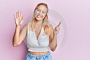 Young blonde girl wearing casual clothes showing and pointing up with fingers number seven while smiling confident and happy