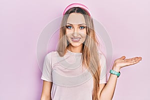 Young blonde girl wearing casual clothes smiling cheerful presenting and pointing with palm of hand looking at the camera