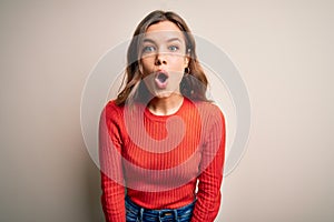 Young blonde girl wearing casual red sweater over isolated background afraid and shocked with surprise expression, fear and