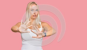 Young blonde girl wearing casual style with sleeveless shirt afraid and terrified with fear expression stop gesture with hands,