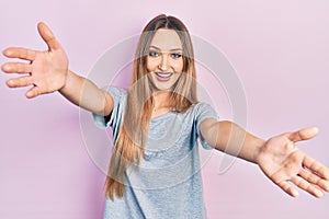 Young blonde girl wearing casual t shirt looking at the camera smiling with open arms for hug