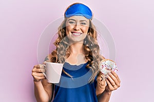Young blonde girl wearing sleep mask and pyjama having breakfast smiling with a happy and cool smile on face