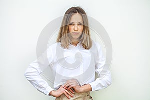 Young blonde girl in white blouse -  on white wall background