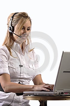 Young blonde girl working on laptop with headset