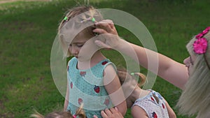 Young blonde hippie mother having quality time with her baby girls dancing in a park - Daughters wear similar dresses