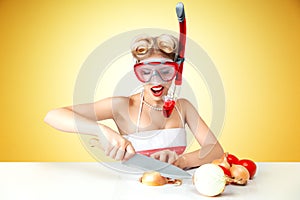 Young blonde housewife chopping onion in diving mask