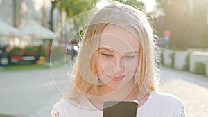 Young Blonde Lady Using a Phone in Town