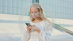Young Blonde Lady Walking and Using a Phone in Town