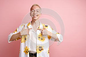 Young blonde laughing man pointing fingers at himself