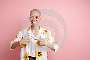 Young blonde laughing man pointing fingers at himself