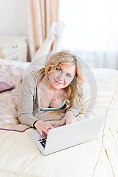 Young blonde lying on her bed using laptop at home in the bedro