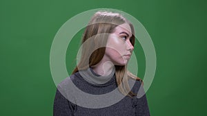 Young blonde model watching sidewards being thoughtful isolated on green chromakey background.