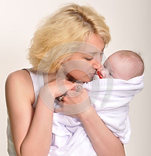 Young blonde mother holds her muffled baby