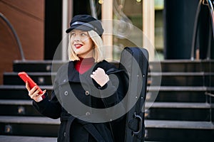 Young blonde musician woman using smartphone at music academy