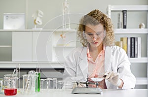 Young blonde scientist  measuring the chemicals for an experiment. Working atmosphere in chemical laboratory. Test tubes and