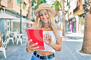 Young blonde tourist girl smiling happy using touchpad at the city